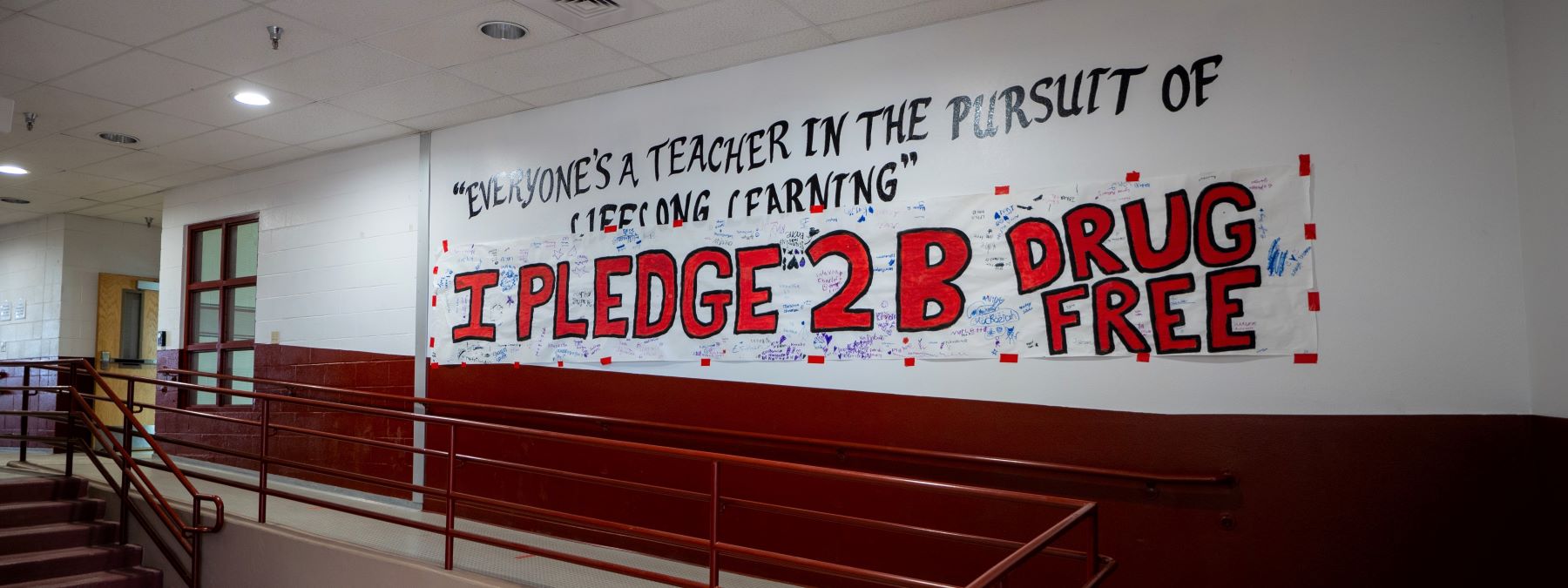 Banners in school hallway, one banner reads; everyone's a teacher in the pursuit of lifelong learning and the other reads I pledge 2b drug free.