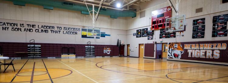School gym with a basketball court and signs on the walls.